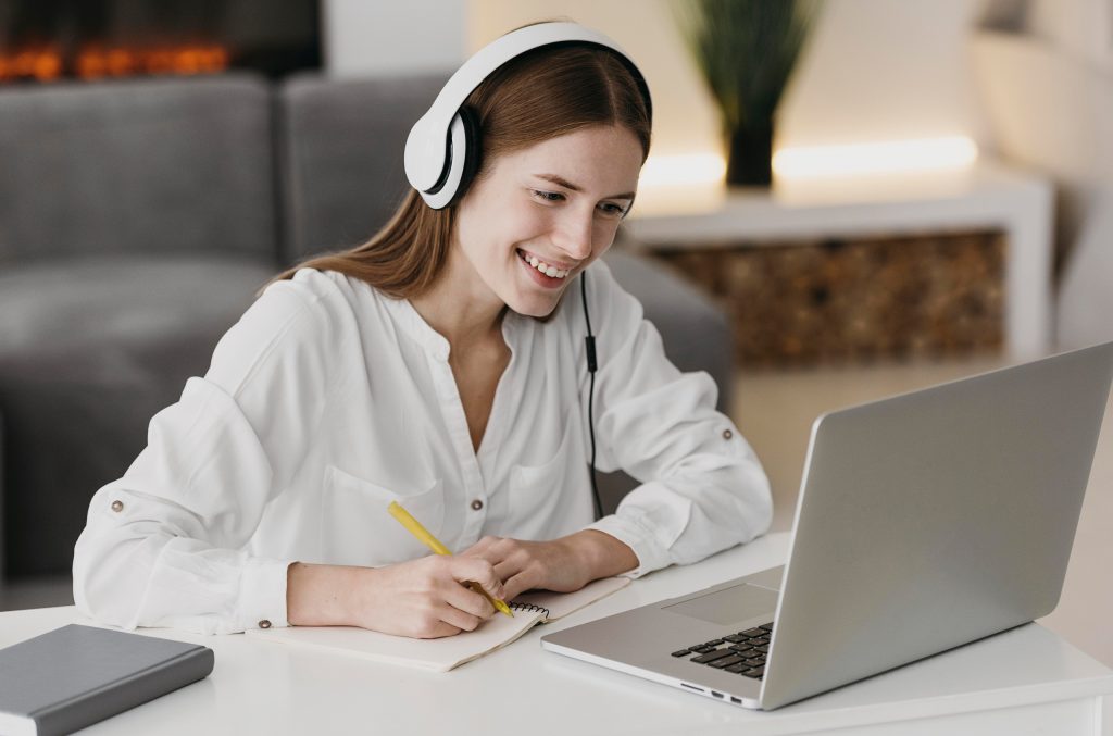 femeie cu căștile pe cap care învață online
